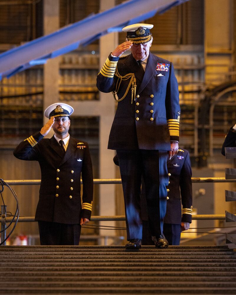 The King and senior submariners salute during his visit to the naval base