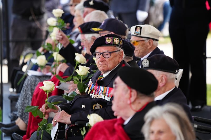 Veterans holding roses which they received from schoolchildren during the event in Normandy