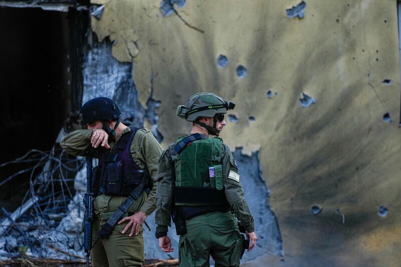Israeli soldiers walk past houses destroyed by Hamas militants in Kibbutz Be’eri (Ariel Schalit/AP)