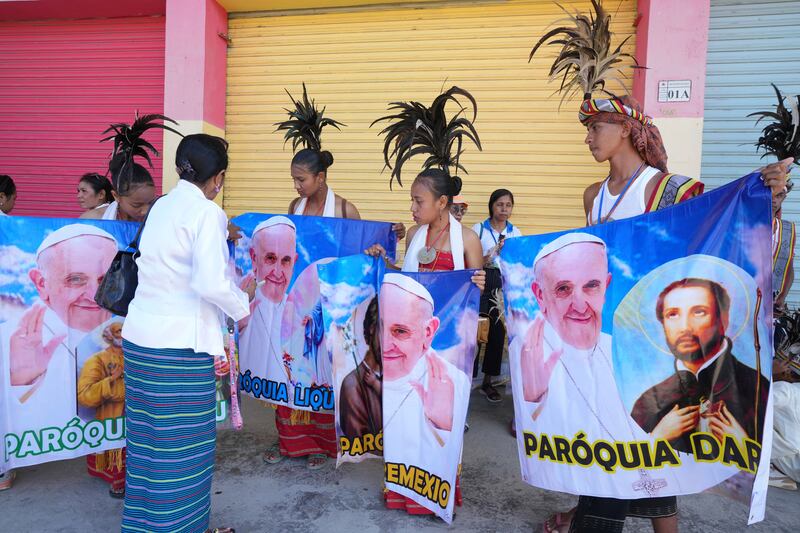 People with traditional dress hold banners of Pope Francis as they prepare to welcome the pope’s visit (Firdia Lisnawati/AP)