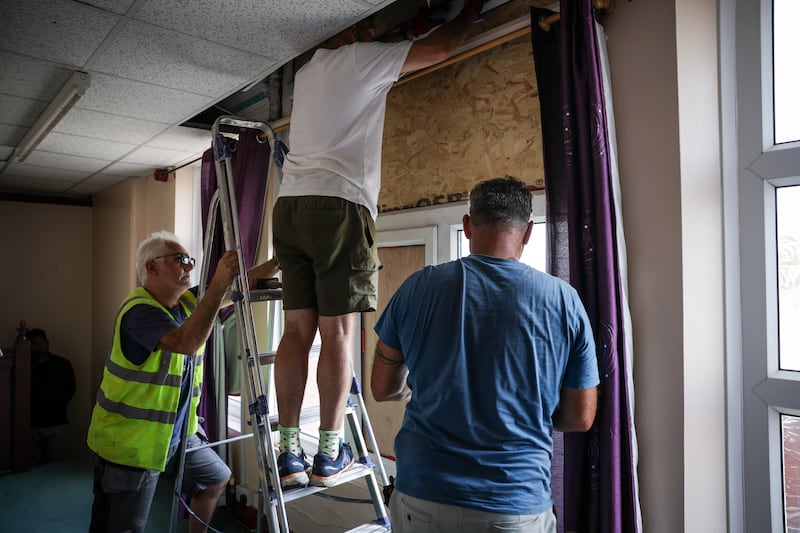 Workers repair a window in the roof of Southport Islamic Centre Mosque in Southport