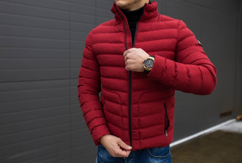 Young handsome guy in a warm knitted clothes against a background of black wall