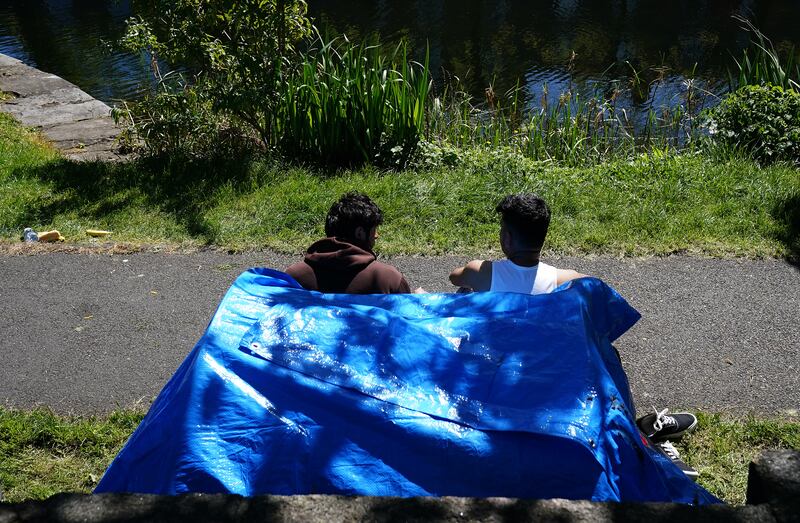 Two people sit outside one of the dozens of tents