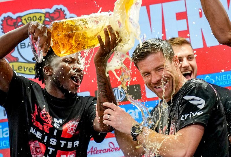 Xabi Alonso, centre, is doused with beer as Bayer Leverkusen celebrate the Bundesliga title after beating Werder Bremen (Martin Meissner/AP)