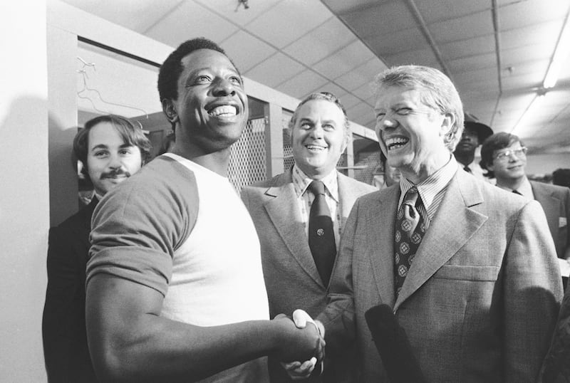 Then-Georgia governor Jimmy Carter, right, and Delaware governor Sherman Tribbitt say hello to Atlanta Braves Hank Aaron, left (Anonymous/AP)