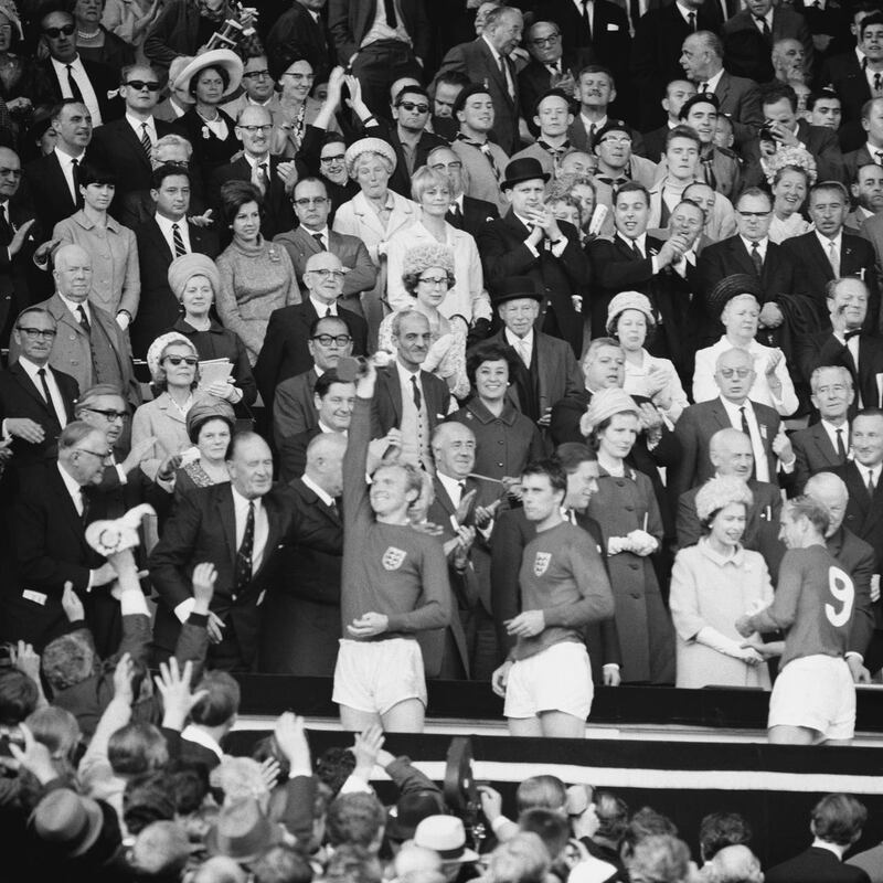 The Queen smiles and shakes hands with Sir Bobby Charlton after presenting his World Cup winners' medal