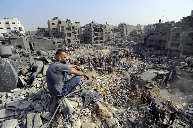 A man sits on the rubble as others wander among debris of buildings that were targeted by Israeli airstrikes in Jabaliya refugee camp, northern Gaza Strip 