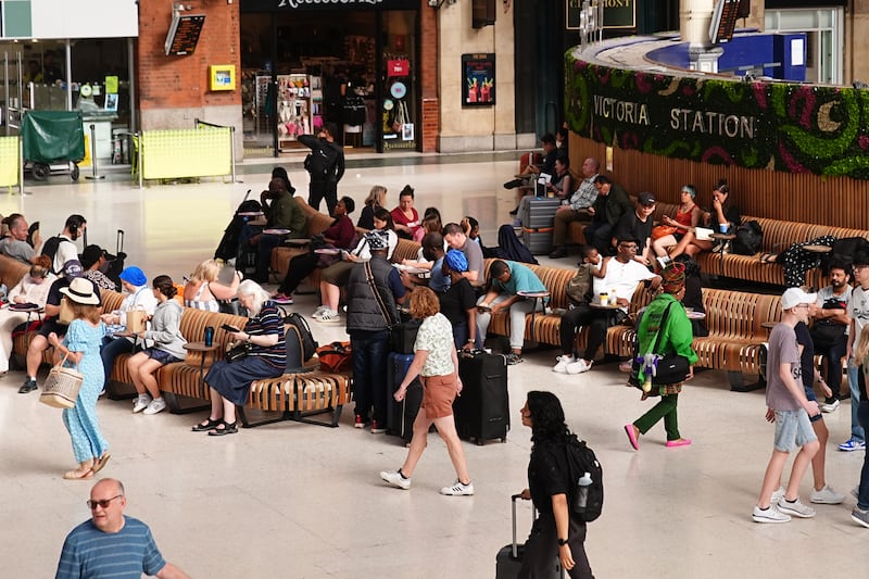 Passengers wait at Victoria railway station in London as services are affected by the IT outage