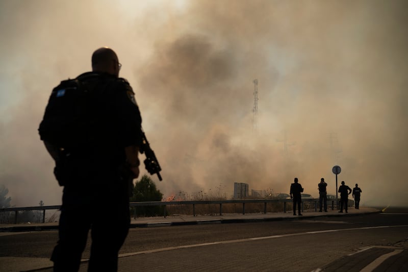 Israeli police stand next to a site of a fire after a rocket, fired from Lebanon, hit an area near the town of Rosh Pinna, northern Israel, on Sunday (Leo Correa/AP)