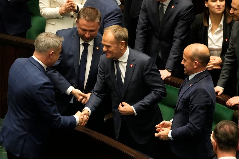 Newly elected Poland’s Prime Minister Donald Tusk, center, is congratulated by lawmakers after his government passed a confidence vote at the parliament (AP Photo/Czarek Sokolowski)