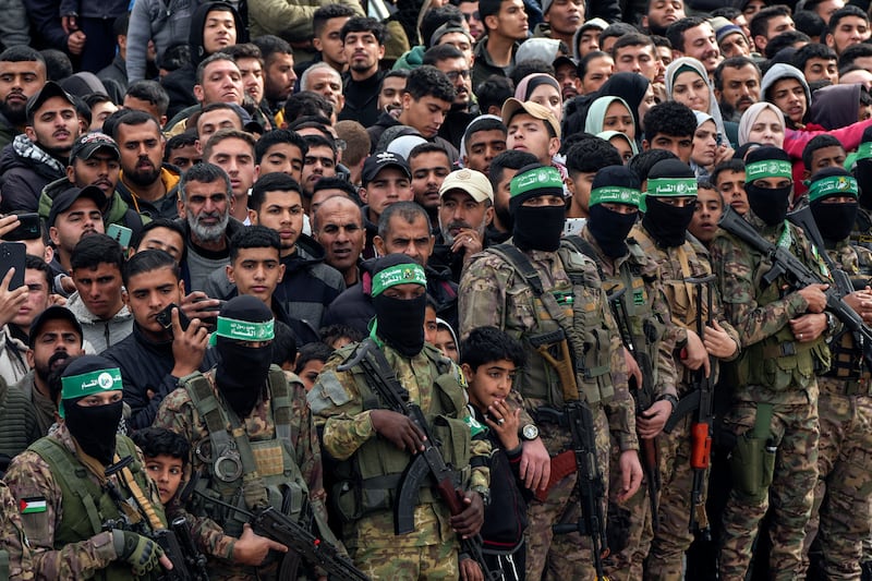 Palestinians watch as Hamas fighters stand in formation (Abdel Kareem Hana/AP)