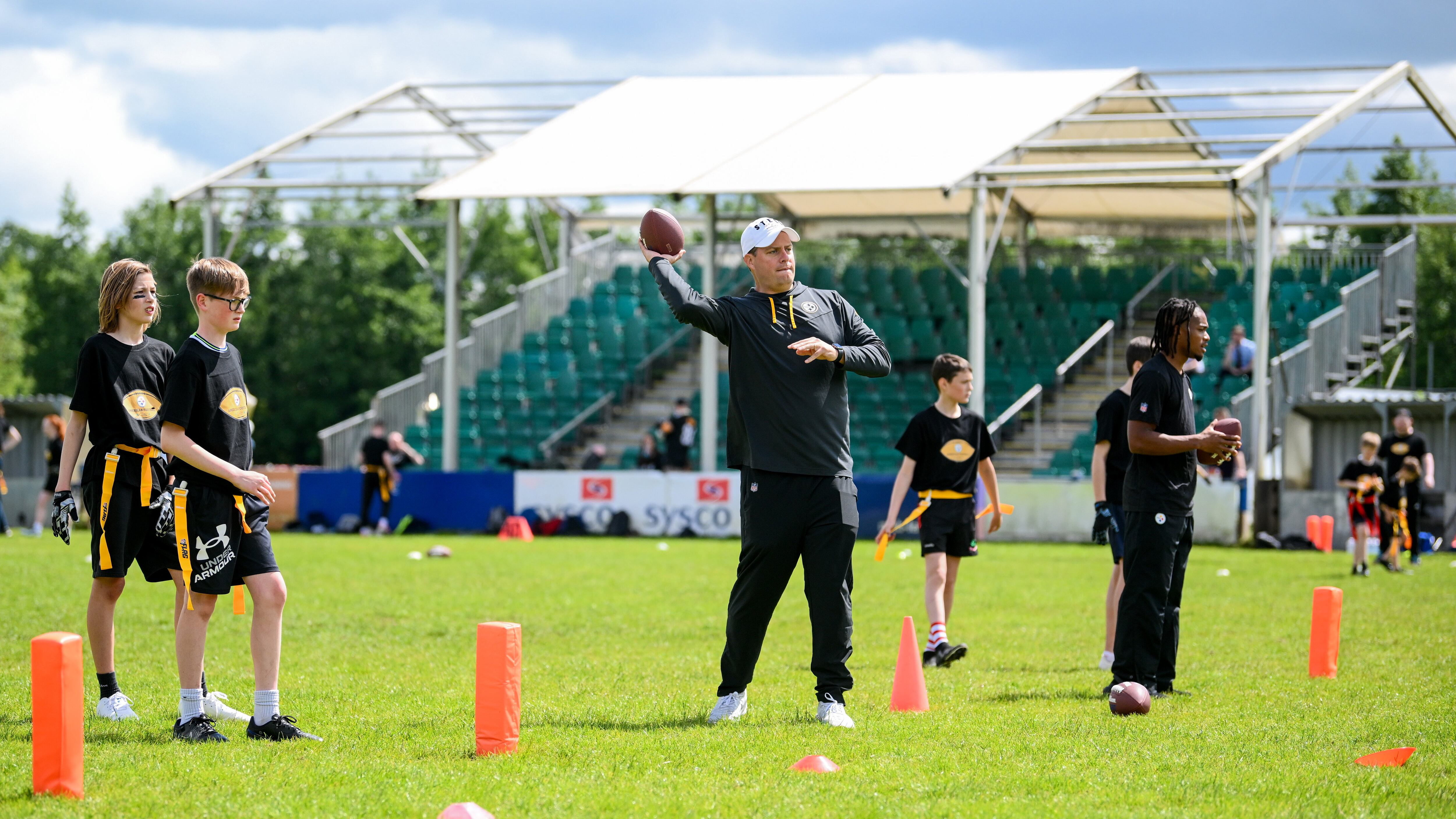 Daniel Rooney of the Pittsburgh Steelers throwing a football with kids at Deramore Park in Belfast during the Steelers Youth Camp