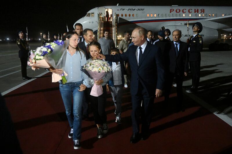 Russian President Vladimir Putin walks with released Russian prisoners and relatives upon their arrival at the Vnukovo government airport outside Moscow, Russia, (Mikhail Voskresensky, Sputnik, Kremlin Pool Photo via AP)