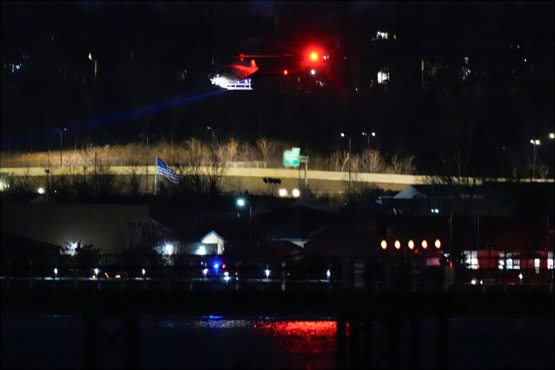 A helicopter uses its searchlight as it flies above the Potomac River near Ronald Reagan Washington National Airport (AP Photo/Alex Brandon)