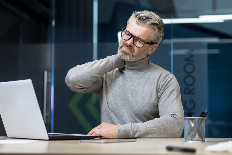 Senior mature businessman working inside office building experiencing neck pain