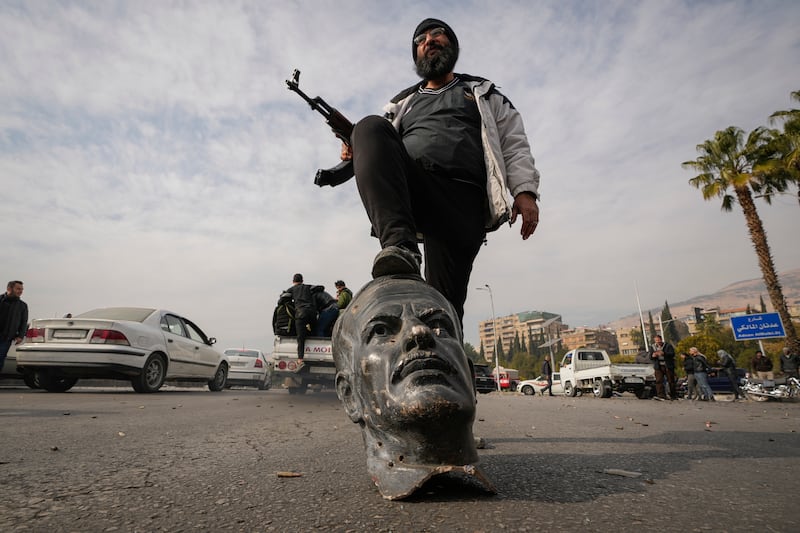 An opposition fighter steps on a broken bust of the late former Syrian president Hafez Assad (Hussein Malla/AP)