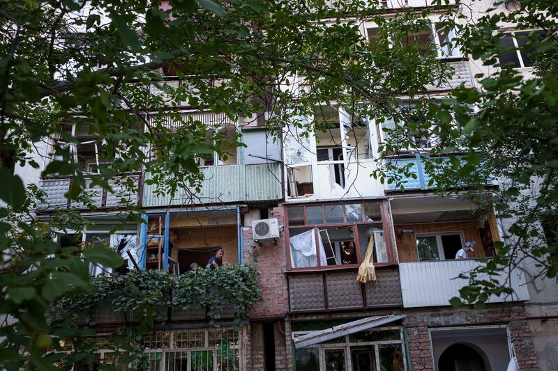 Residents clear broken glass from their balconies after a Russian bombardment of a residential neighbourhood in Pokrovsk, Donetsk region, Ukraine in August (Evgeniy Maloletka/AP)