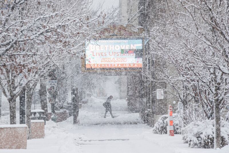 A pedestrian makes their way along 2nd Street SE as snow falls in Cedar Rapids, Iowa (Nick Rohlman/AP)