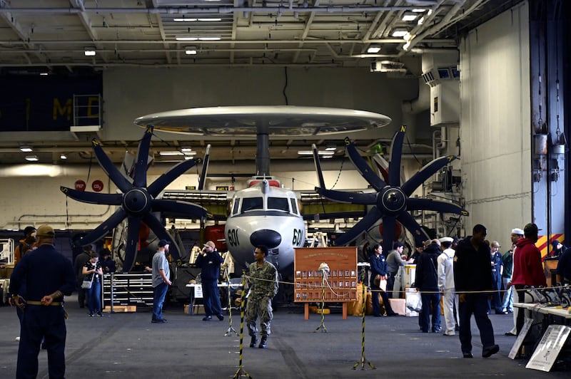 Crew members walk past aircraft in the hangar of the Theodore Roosevelt, anchored in Busan Naval Base in South Korea (Song Kyung-Seok/Pool Photo via AP)
