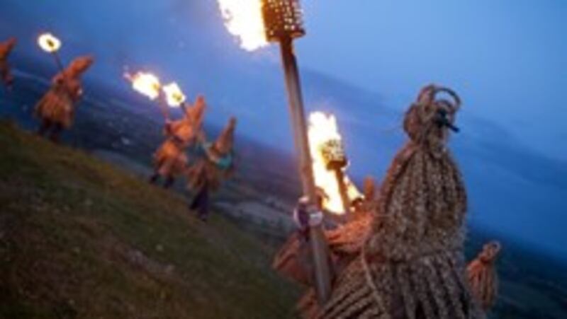 Image of men in ceremonial dress holding holding sticks of fire.