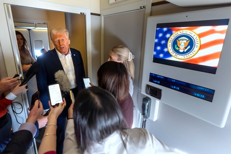 Donald Trump speaks to reporters aboard Air Force One (Mark Schiefelbein/AP)