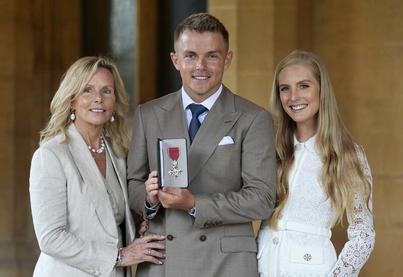 Sam Curran with his mother Sarah (left) and partner Isabella after being made a Member of the Order of the British Empire by the King