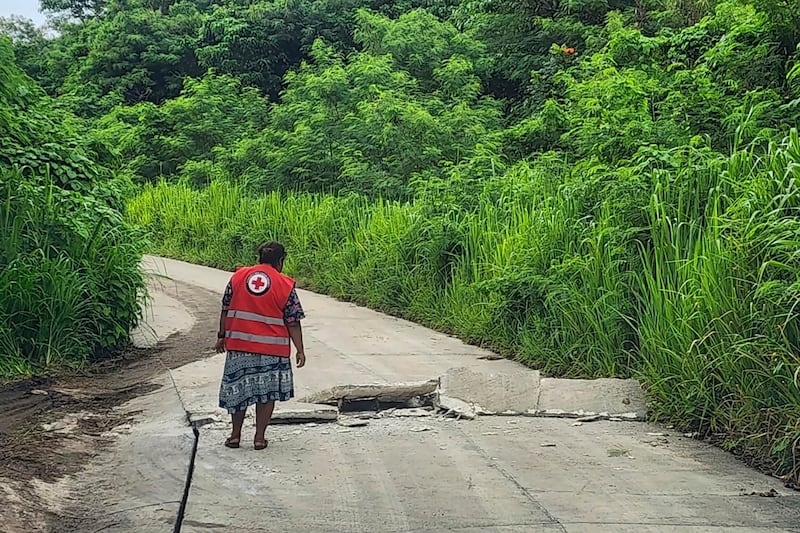 In this photo released by Vanuatu Red Cross Society, a volunteer inspects a damaged road in Efate, Vanuatu (Vanuatu Red Cross Society/AP)