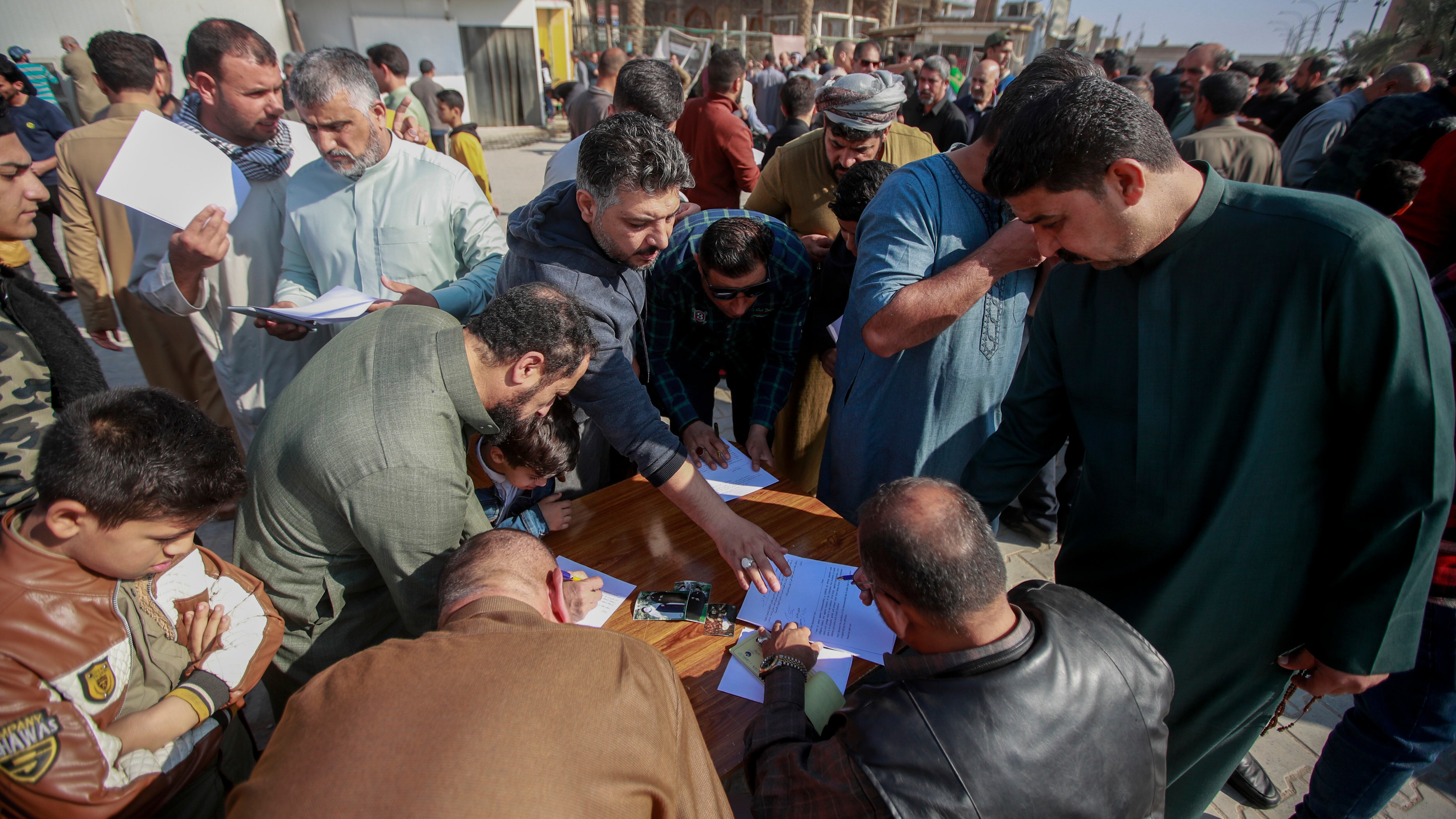 Iraqis sign a pledge to stand against homosexuality outside a mosque in Kufa (Anmar Khalil/AP)