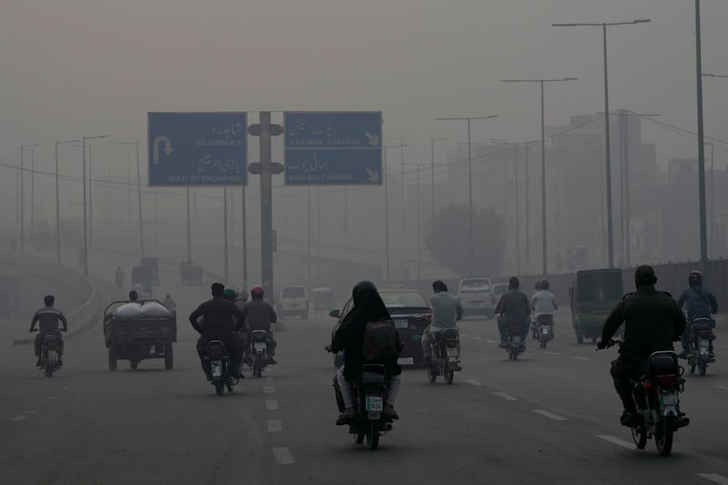 Motorcyclists as smog envelops the city (K.M. Chaudary/AP)