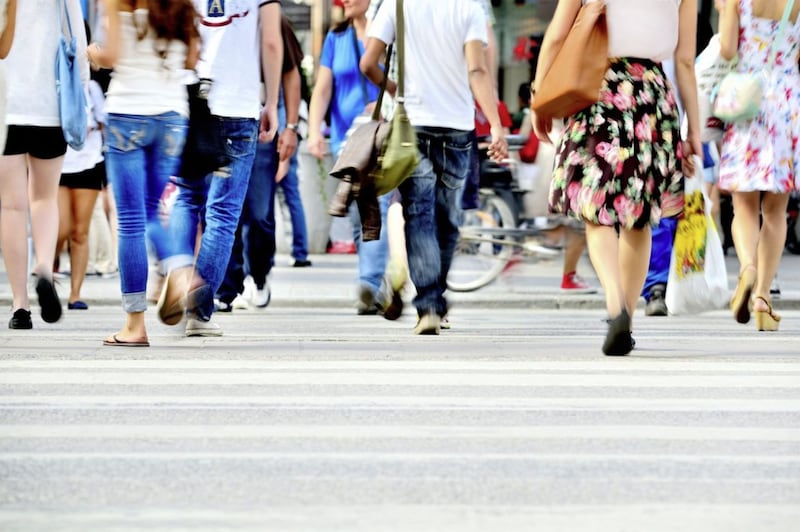 Motion blurred pedestrians crossing sunlit street 