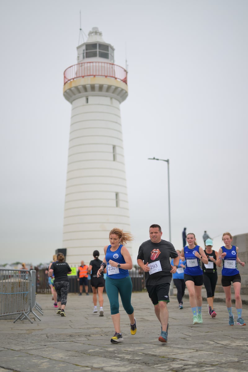 Group of runners in 5k race in front of white lighthouse