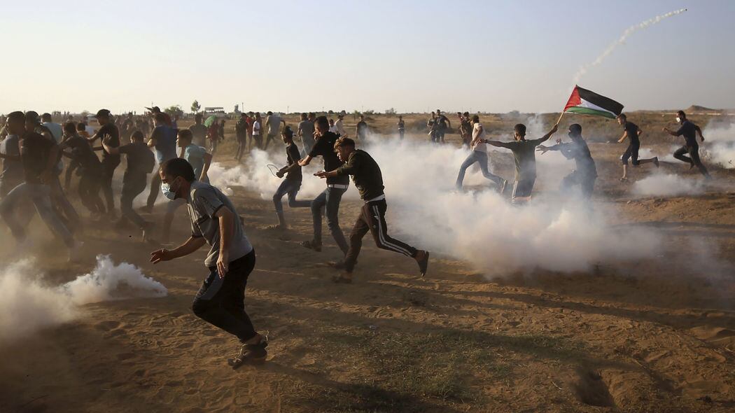 Protesters run and take cover from teargas fired by Israeli troops near the fence of Gaza Strip border with Israel during a protest east of Khan Younis, southern Gaza Strip, Wednesday, August 25, 2021 (AP Photo/Abdel Kareem Hana)&nbsp;