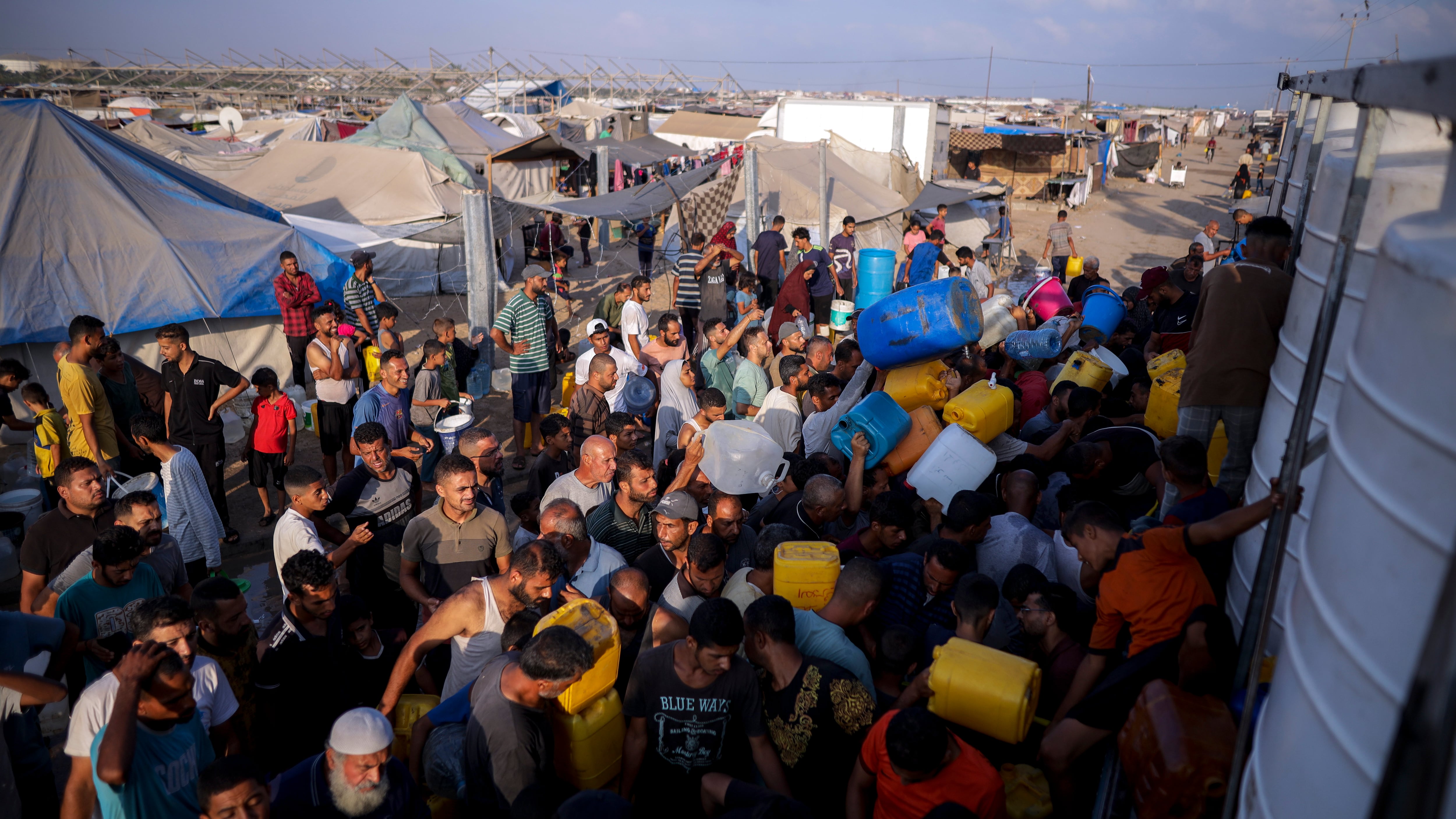 Palestinians displaced by the Israeli bombardment of the Gaza Strip queue for water at a makeshift tent camp in the southern town of Khan Younis on Monday (Jehad Alshrafi/AP)