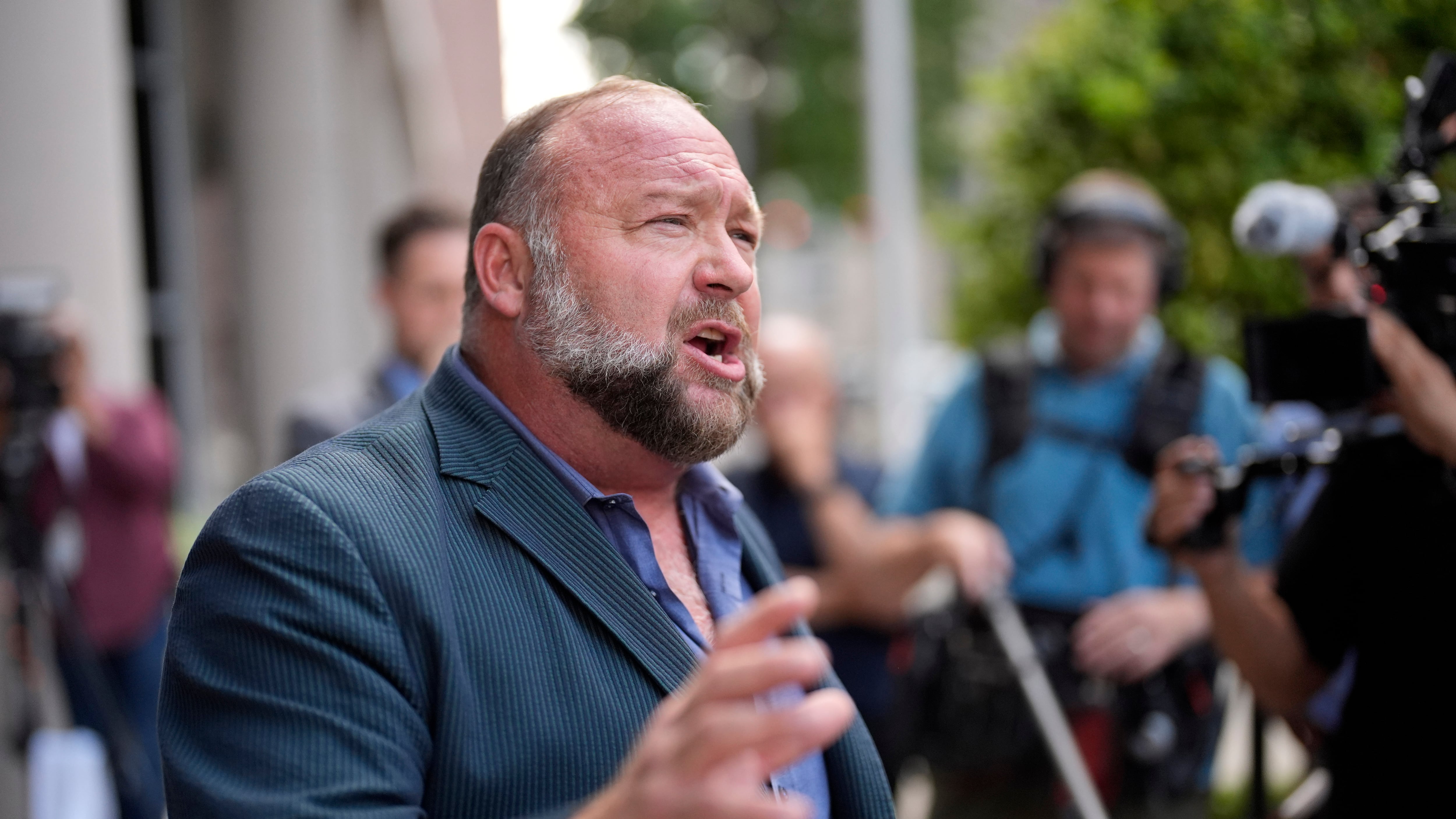Conspiracy theorist Alex Jones speaks to the media after arriving at court for an earlier hearing (David J Phillip/AP)