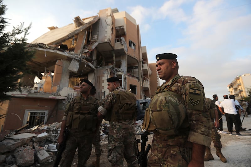 Lebanese soldiers next to a destroyed building hit by an Israeli air strike south of Beirut (Mohammed Zaatari/AP)