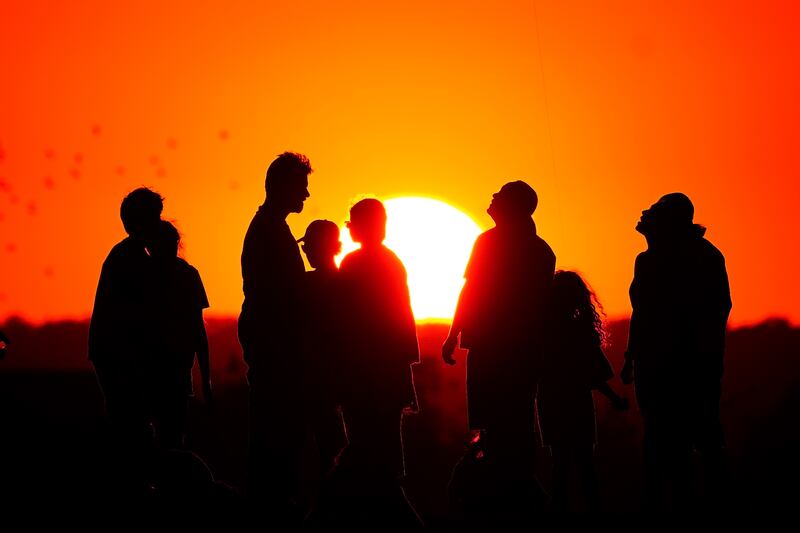 A crowd of people watch the setting sun from a hill in Ealing, west London