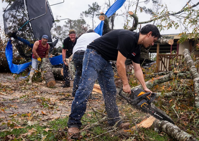 Ricardo Rodriguez uses a chain saw to remove debris from a woman’s home after strong thunderstorms pass through the Greater Houston region in Porter Heights (Jason Fochtman/Houston Chronicle/AP)