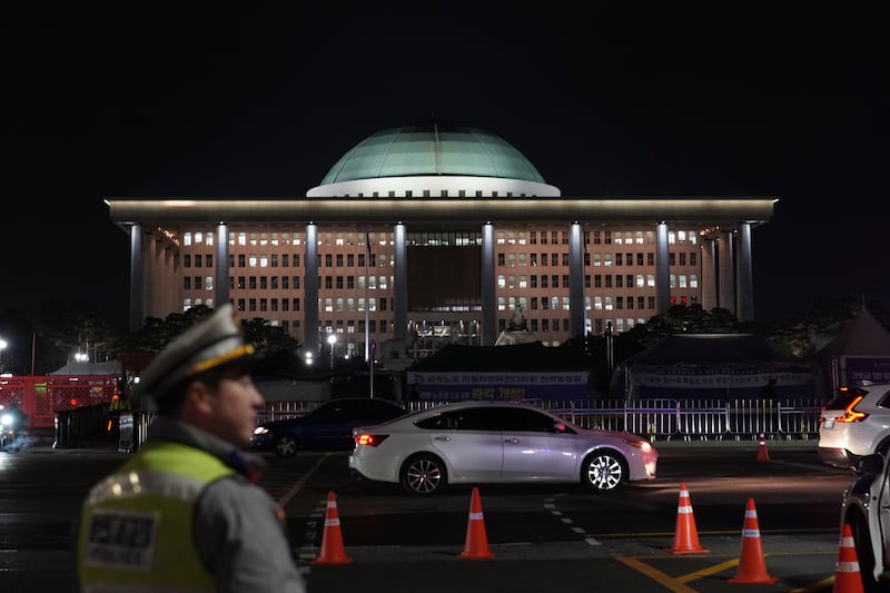 A traffic police officer walks near the National Assembly as a rally demanding South Korean President Yoon Suk Yeol’s impeachment is taking place, in Seoul (Lee Jin-man/AP)