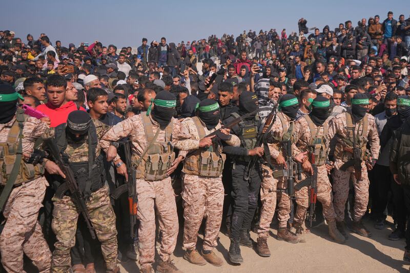 Hamas and Islamic Jihad fighters contain the crowd as cars carrying Israeli Gadi Mozes and Arbel Yehoud are escorted to be handed over to the Red Cross in Khan Younis (AP Photo/Abdel Kareem Hana)