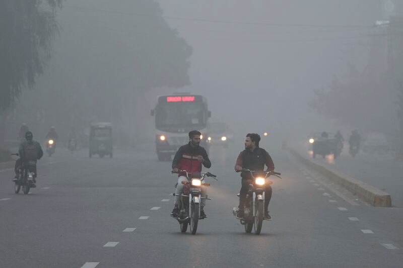 Vehicles and motorcyclists travel with headlights on due to reduced visibility caused by smog in Lahore, Pakistan (KM Chaudary/AP)