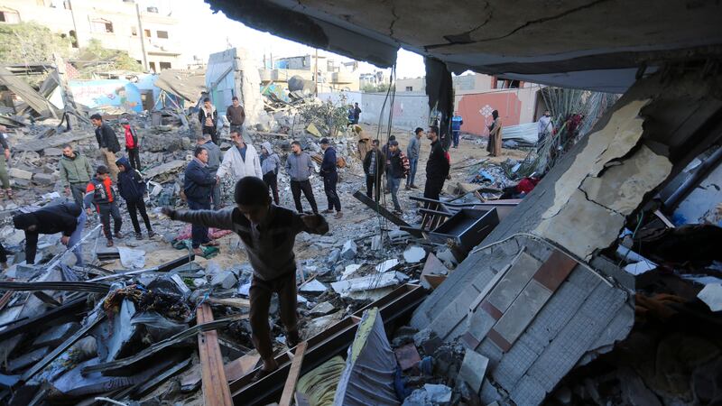 Palestinians stand by a building destroyed in an Israeli bombardment in Rafah in the Gaza Strip