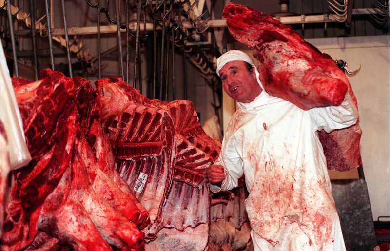 A Smithfield market butcher at work among beef carcasses