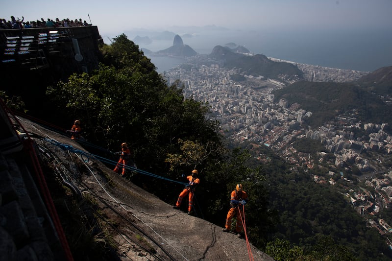 Trash collectors rappel down Corcovado Mountain to remove garbage dumped on the slope of the Christ the Redeemer Statue in Rio de Janeiro (Bruna Prado/AP)