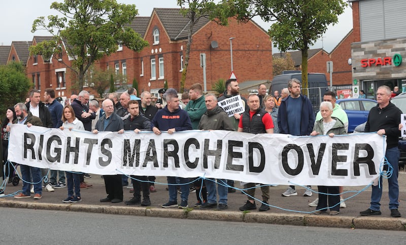 A parade passes the Ardoyne shop fronts from  the Woodvale area in North Belfast on Saturday Morning , as protesters line the street.PICTURE COLM LENAGHAN