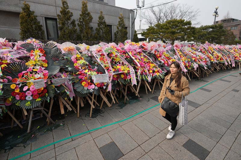 A woman passes wreaths sent by supporters of impeached South Korean President Yoon Suk Yeol outside the Constitutional Court in Seoul (Lee Jin-man/AP)