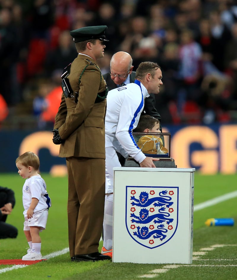 Wayne Rooney, centre, received a commemorative golden cap from fellow centurion Sir Bobby Charlton to mark his 100th England appearance