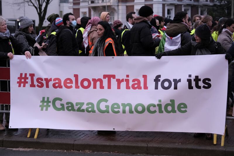 People stand by a banner outside the International Court of Justice (Patrick Post/AP)