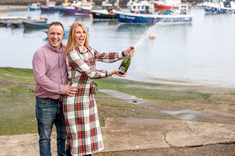 Couple celebrate with a bottle champagne which is over spilling