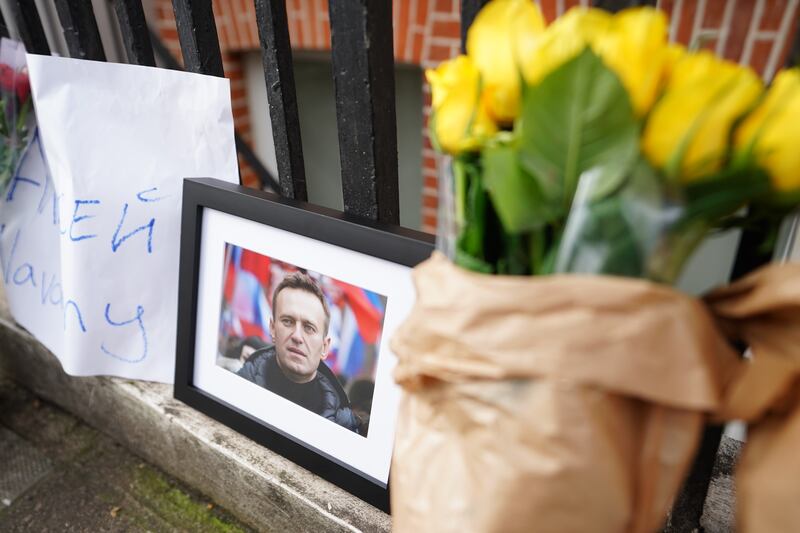 An image of Alexei Navalny alongside floral tributes placed close to the Russian Embassy in London