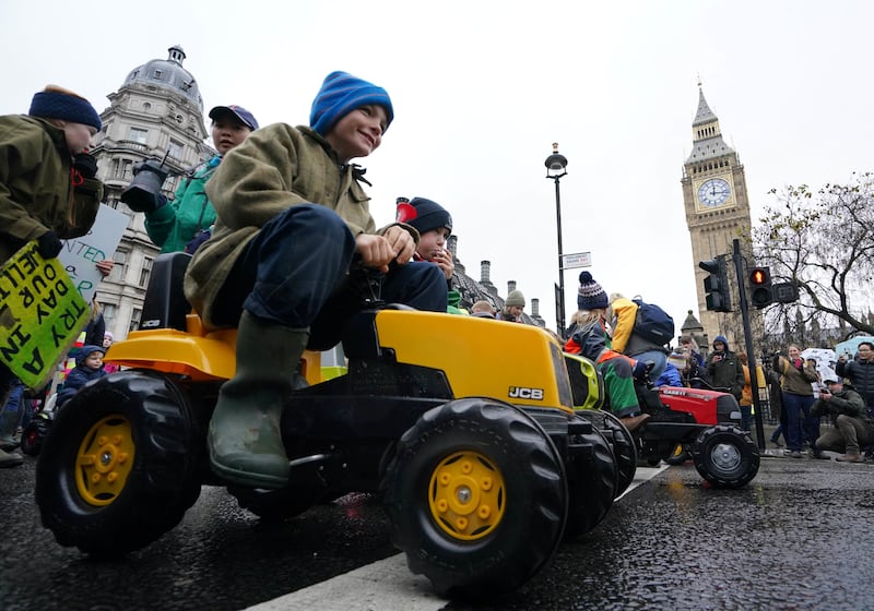 Children ride on toy tractors as part of the farmers’ protest in central London